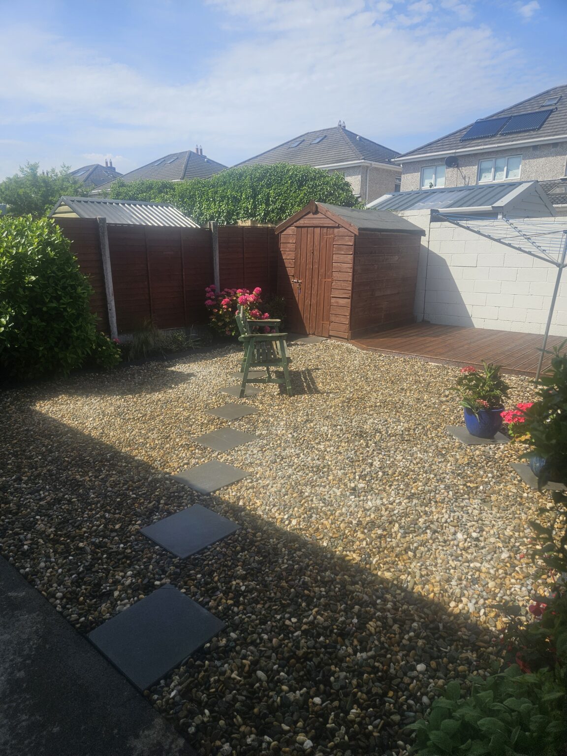 finished garden with decoratìve gravel , stepping stones, flower bed edging and fresh fence and decking painting