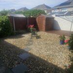 finished garden with decoratìve gravel , stepping stones, flower bed edging and fresh fence and decking painting
